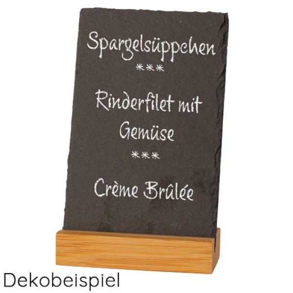 Hochkant stehende dunkle Schiefertafel, beschriftet mit natürlicher Bruchkante in einem hellen, stabilen Sockel aus Bambus.